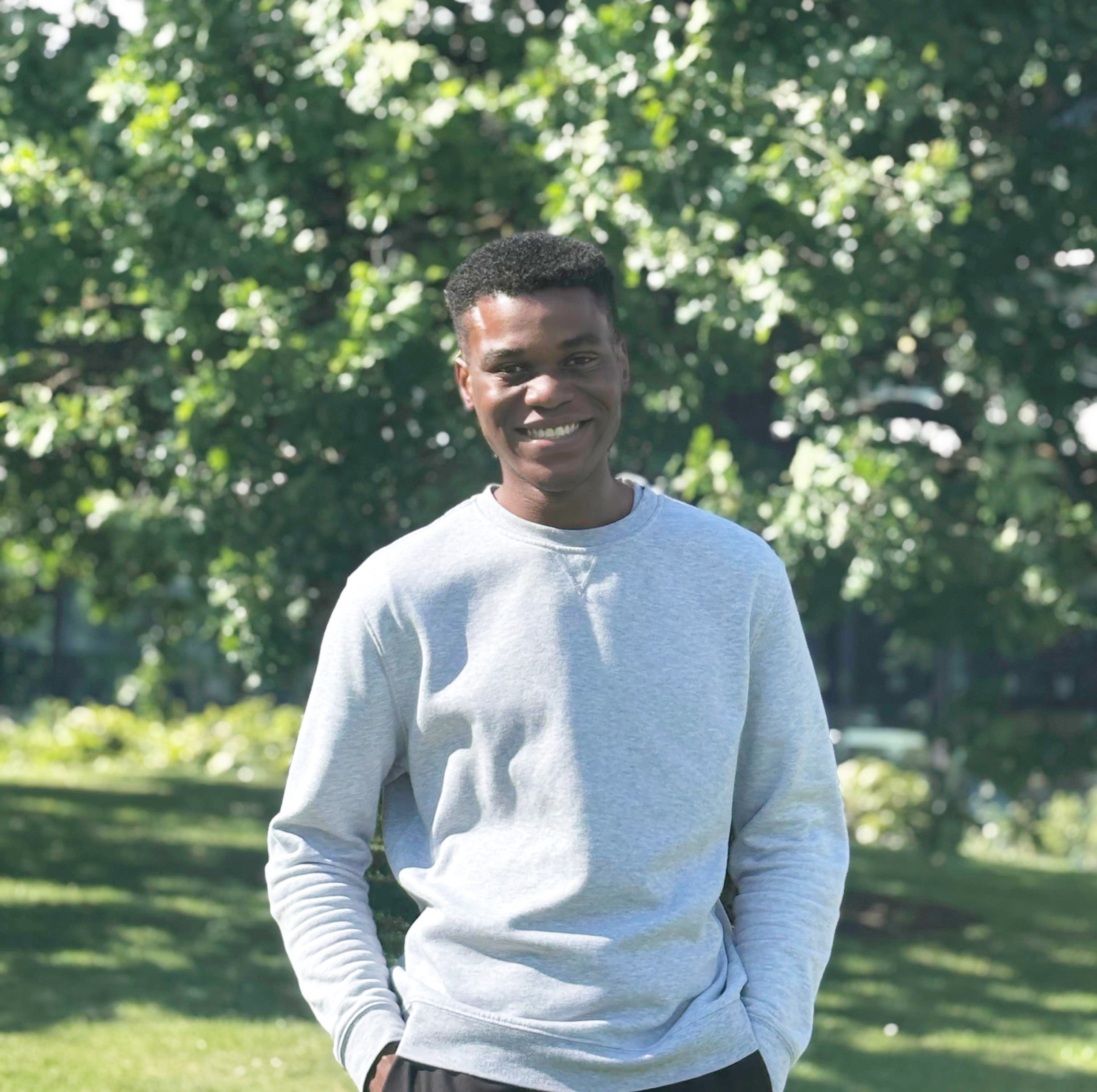 A student standing in front of greenery.